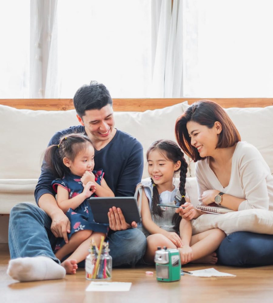 Happy Asian family using tablet, laptop for playing game watching movies, relaxing at home for lifestyle concept